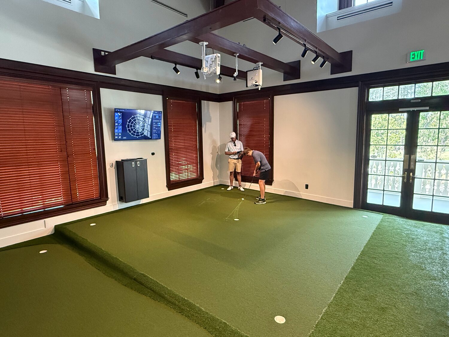 Governors Towne: the raised TOURPUTT Circle putting green under timber beams, with two golfers putting at the far side