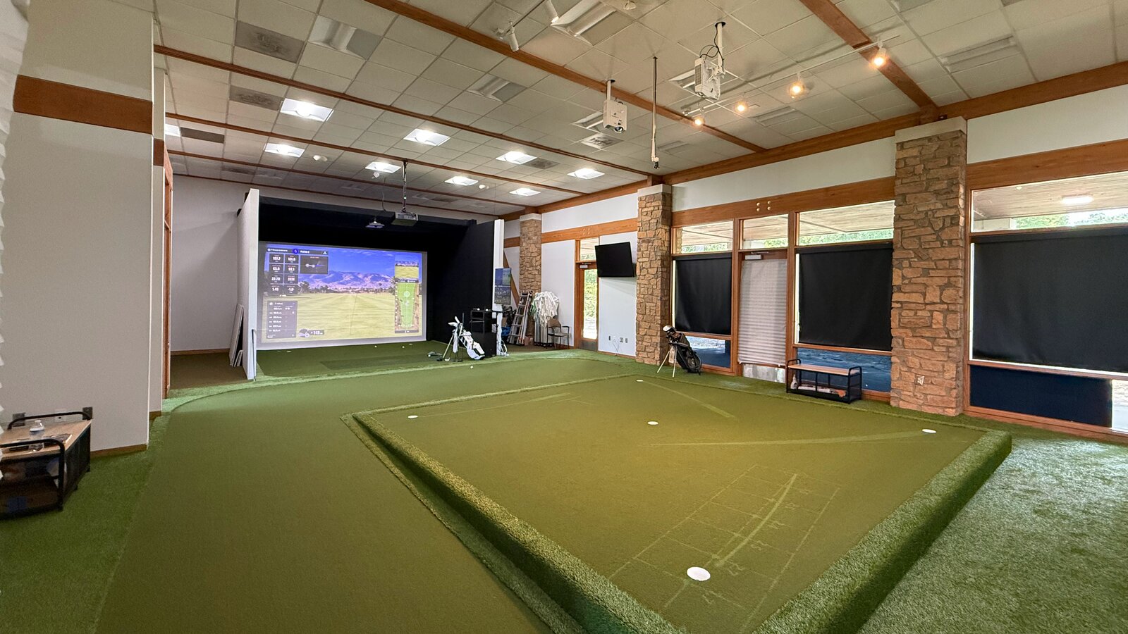 After: a raised putting green and a simulator bay where the classroom tables stood