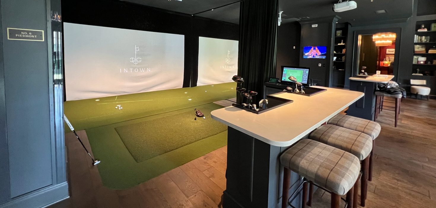 Intown Golf Atlanta: simulator bays with a putting green and a bar counter with stools