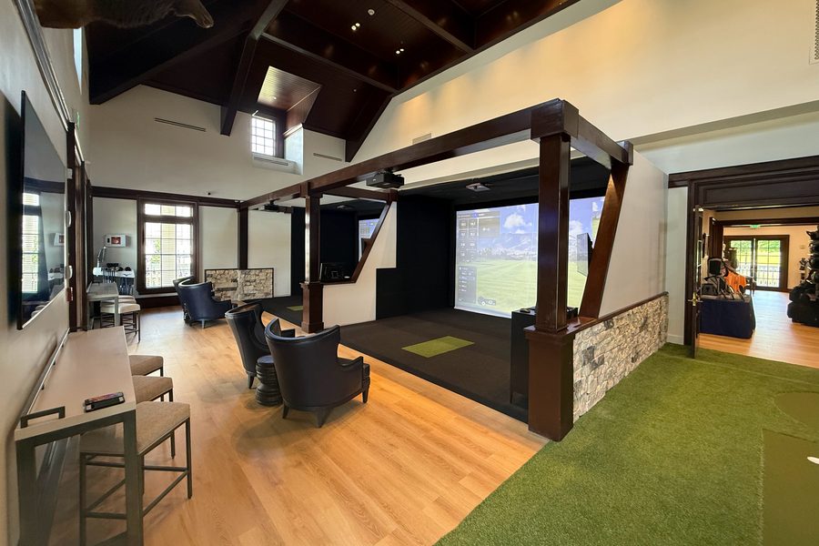 Governors Towne: a timber-framed simulator bay with lounge seating beside a putting green