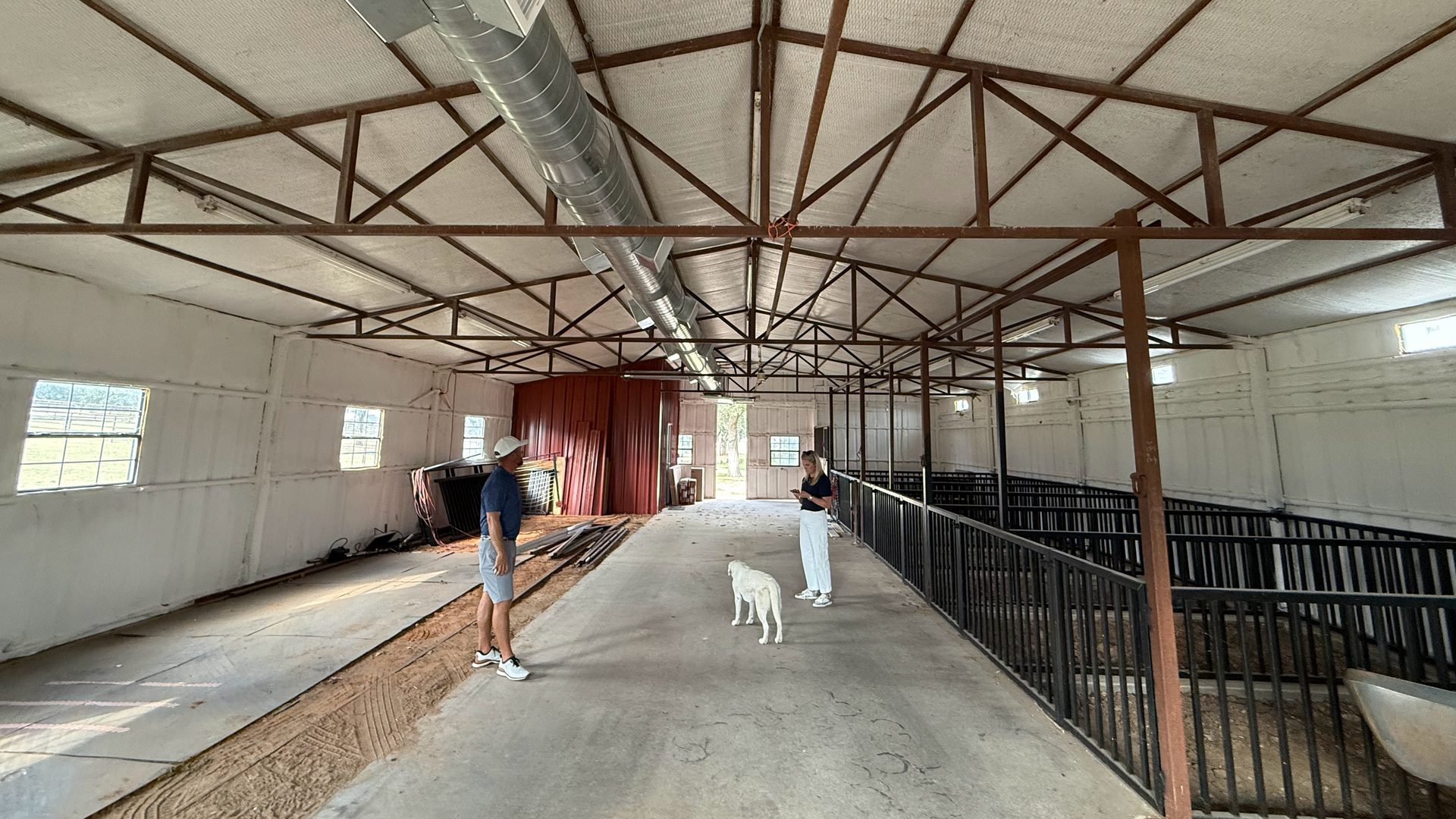 Before: the empty horse barn with stalls and a concrete floor