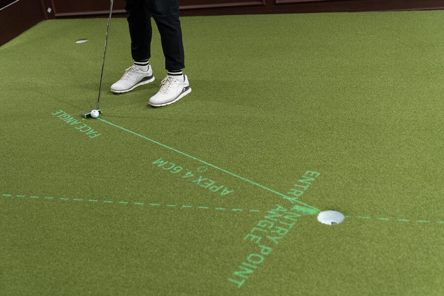 A projected putt line on the green with the apex and the entry point labelled near the hole
