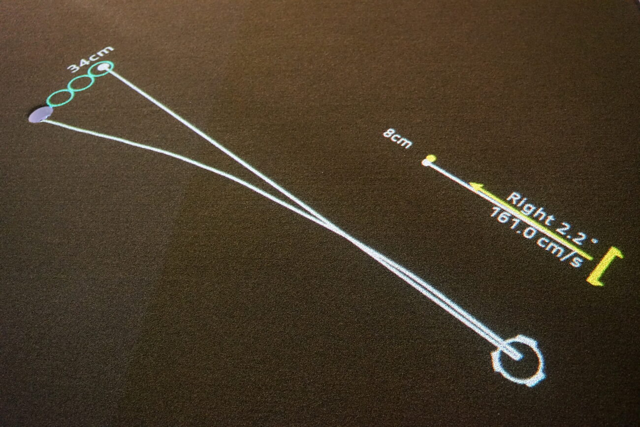The traced paths of a putt drawn on the green from the ball to the hole, with distance and launch figures beside them